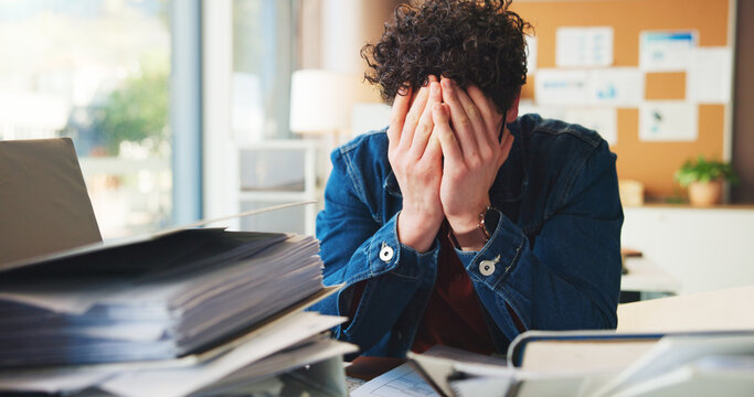 Overwhelmed, man or burnout in office with workload for marketing proposal, document pile or deadline. Upset, employee and creative person with stress for paperwork, pressure or information overload. - Powered by Adobe