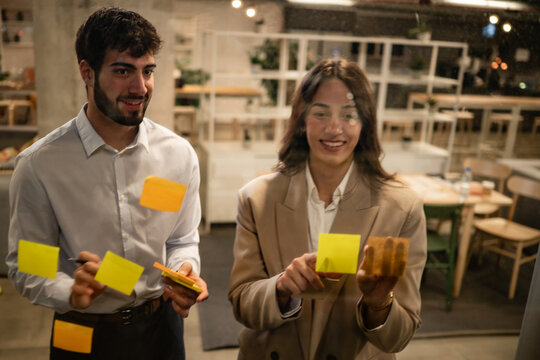Coworkers brainstorming ideas on sticky notes at office meeting - Powered by Adobe