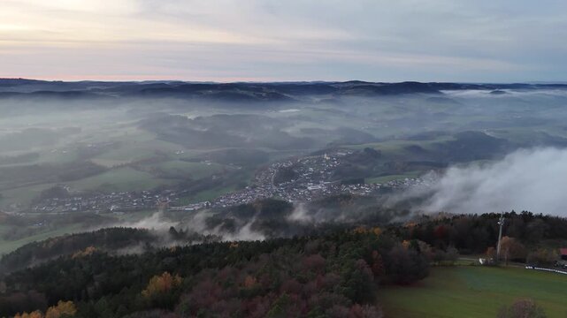 Drone captures the Bavarian Forest in Straubing Bogen district covered in ground fog with trees illuminated by warm evening light in peaceful autumn scenery