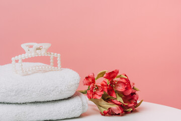 Spa towels with pearl hair clip and flowers on pink. High quality photo