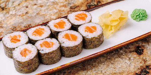 Delicious sushi rolls served with ginger and wasabi on a decorative plate