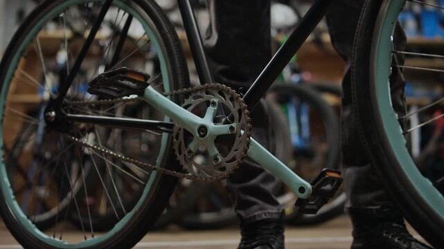 Medium close-up of unrecognizable men checking bicycle drivetrain system in repair workshop