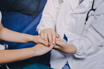 Doctor giving hope. Close up shot of young female physician leaning forward to smiling elderly lady patient holding her hand in palms. Woman caretaker in white coat supporting encouraging old person