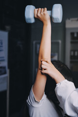 old woman training with physiotherapist using dumbbells at home therapist assisting senior woman...