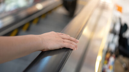 Close-up at people hand is holding on the handrail during riding escalator at the shopping mall.