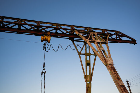 Rusty construction crane against clear blue sky, industrial equipment and urban setting