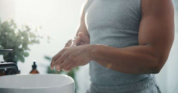 Cream, hands and skincare with man in bathroom of home for daily or morning moisturizing routine. Beauty, body care and lotion with person in apartment for cosmetics, dermatology or wellness