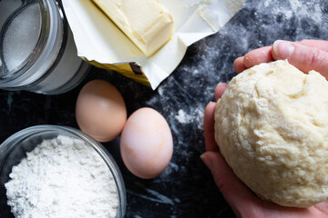 Female hands holding soft dough during the home baking process. Close-up. Rustic kitchen mood, fresh ingredients out of frame. Concept of pastry making and homemade food.