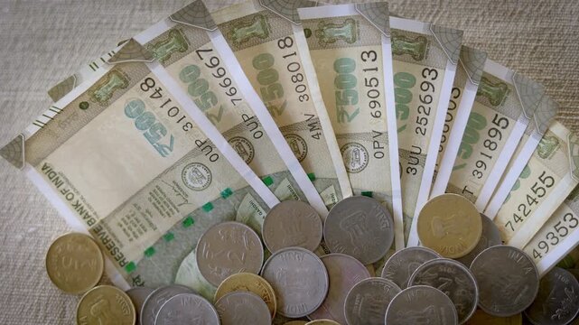 Indian 500 Rupee Banknotes Flying in Wind with Scattered Coins on White Background