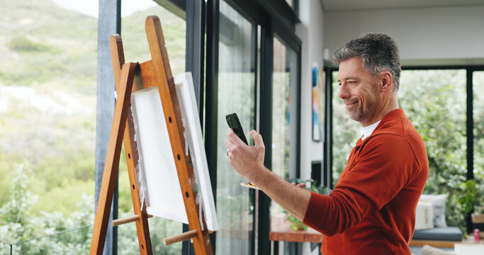 Painting, phone and picture with man in workshop for design reference, artist project and contact. Illustration inspiration, gallery artwork and canvas with mature person in studio for photography