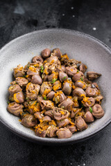 Tasty giblets stew served in gray plate on textured black surface ideal for culinary blogs or traditional meal visuals.
