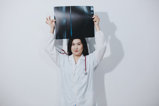 Asian Muslim doctor in hijab and scrubs headphones around her neck Stand confidently in the medical office, isolated on white background, holding x-ray film.