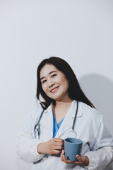 Portrait of Asian doctor woman standing holding coffee cup in white studio background