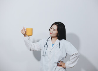 Portrait of Asian doctor woman standing holding coffee cup in white studio background