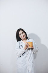 Portrait of Asian doctor woman standing holding coffee cup in white studio background