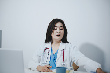 Middle aged female doctor working on laptop in doctor's room