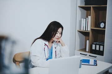 Middle aged female doctor working on laptop in doctor's room