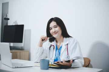 Middle aged female doctor working on laptop in doctor's room