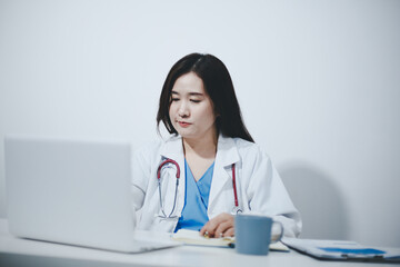 Middle aged female doctor working on laptop in doctor's room