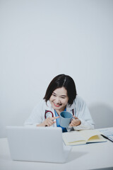 Middle aged female doctor working on laptop in doctor's room