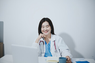 Middle aged female doctor working on laptop in doctor's room