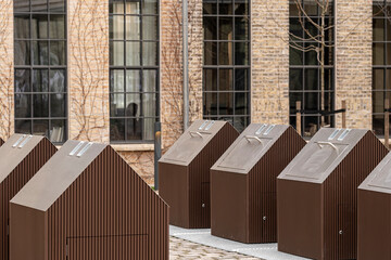 Public waste container placed in an urban exterior area beside functional architecture, combining straightforward design with sustainable ecofriendly cues and visible recycling intent in daylight
