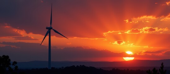 Wind turbine against a vibrant sunset sky with dramatic clouds.