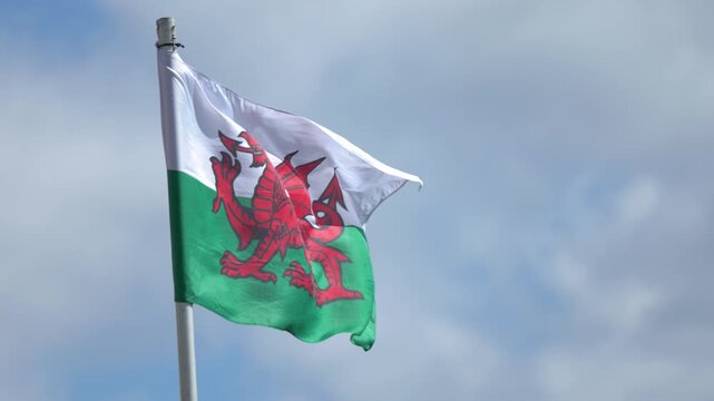 Welsh Flag Fluttering in Wind Against Blue Sky