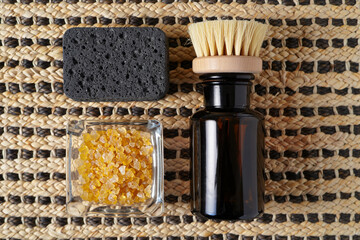 Spa Treatment Still Life with Amber Bottle Sea Salt Pumice Stone and Brush on Woven Mat