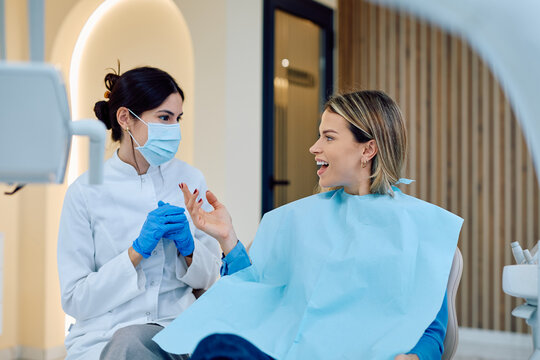 Woman patient having a consultation with a dentist wearing a protective mask and gloves in a modern dental clinic