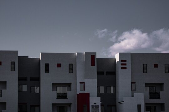 Modern white apartment buildings with geometric design and dark windows under a moody sky, showcasing contemporary urban architecture - Powered by Adobe
