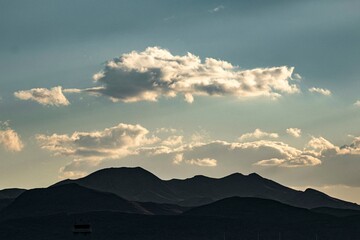 Scenic silhouette of mountain range under a cloudy sky during sunset with soft natural lighting and peaceful atmosphere