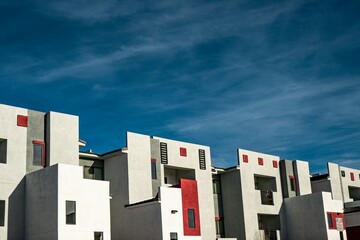 Modern white and red apartment buildings under a deep blue sky showcasing contemporary urban residential architecture