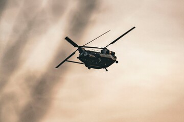 Military helicopter flying over a cloudy sky with a vintage sepia tone effect creating a dramatic atmosphere