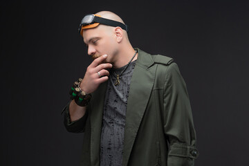 Dystopian portrait of charismatic bald man in textured raincoat with head goggles