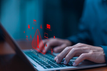 A businessman is using a laptop with a cybersecurity alert warning on the screen, preventing cyber threats in systems and digital environments. data systems warning, fraud. danger cyber attack