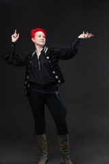 A bold and bright young woman with short bright scarlet hair in a vintage black suit with a stylish vest in a rich pirate style , photo on dark gray