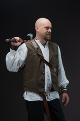 Wealthy medieval character: bald man in vest holding axe, studio gray background.