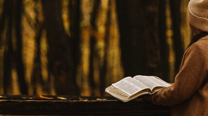 person reading a book outdoors in a forest setting with soft lighting