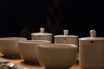 Tea ceremony with white ceramic teapot and cups on wooden table