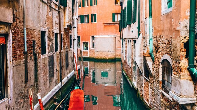 Narrow venetian canal lined with old buildings and reflections - Powered by Adobe