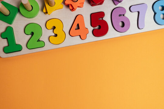 Wooden Numbers Puzzle for Preschool Counting and Number Learning. Wooden educational puzzle with colorful numbers from one to eight, placed on an orange background.