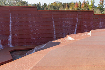 Architectural water feature with cascading terraces, where water flows down rust-colored steps, creating a dynamic scene. Water amphitheater or canyon in Krasnodar's city park, or Galitsky Park