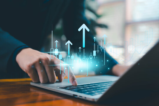 Business person using laptop with digital financial growth chart, rising arrows, and candlestick analytics representing market trends, investment strategy, fintech innovation, and economic success.