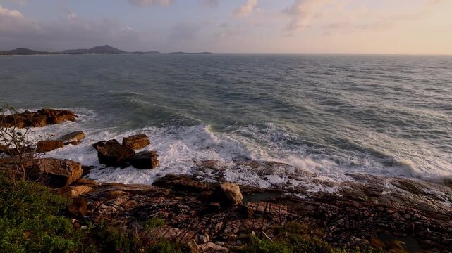 Tropical coastline with waves crashing against rocky cliffs under soft golden sunlight. The timelapse captures the dynamic motion of the sea, the power of nature, and the tranquil beauty of the ocean 