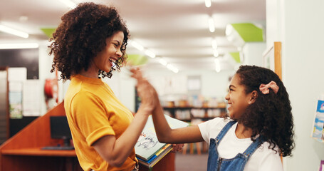 Happy woman, teacher or high five with child in library for education, learning or success. Female person, educator or smile with kid, girl or student for literature, reading or well done in bookshop