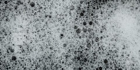 white soap foam texture with small and large air bubbles spread across the surface of the water