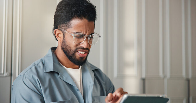 Confused, reading and man with tablet in home with notification, networking or social media. Doubt, error and male person with digital technology for spam text or subscription cancellation in house. - Powered by Adobe
