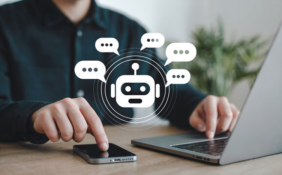A person interacts with a smartphone and laptop, with a digital chatbot icon surrounded by speech bubbles appearing between them, representing ai assistance and communication