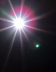 Bright light shining with lens flare effect on a dark background creating a starburst